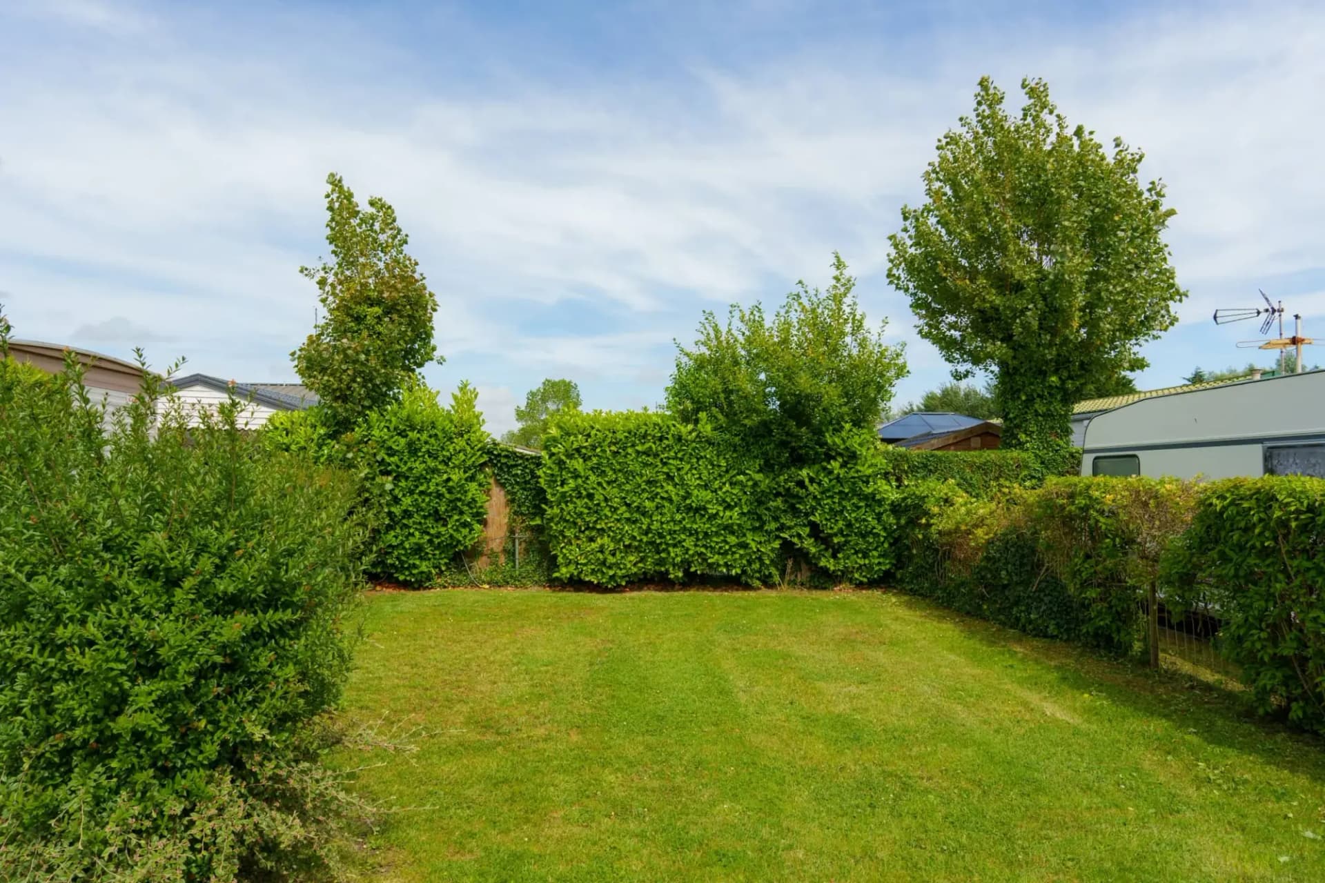 Grand emplacement de camping enherbé bordé de haies