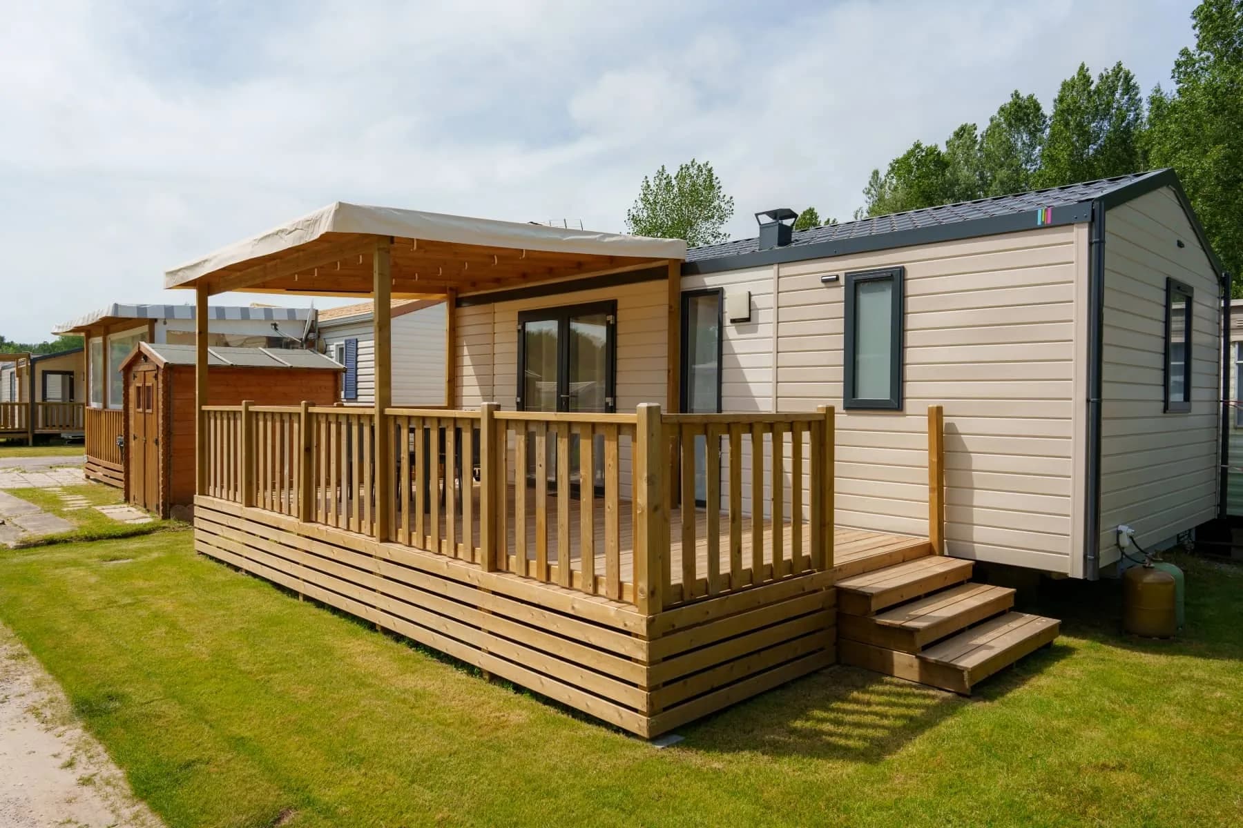 Terrasse couverte d'un mobil-home dans la verdure du camping